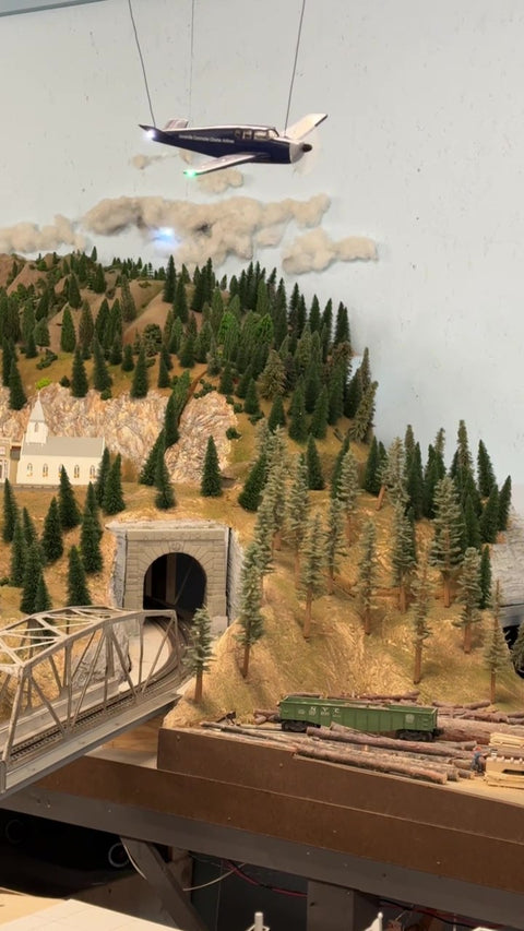 Model Train Scene Featuring Lighted Airplane and Clouds