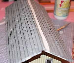 For the roof, print out shingle material and cut it into strips like real roofing. Next cut small slits along the bottom of each piece and bent the edges up to create a 3D effect with the roofing. Glue the strips on to the roof starting at the bottom, work your way up and across leaving a little overhang just as if you were putting on real shingles.